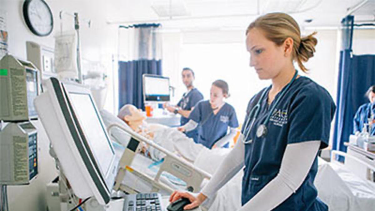 young woman in scrubs at computer at the Pace University Lienhard School of Nursing