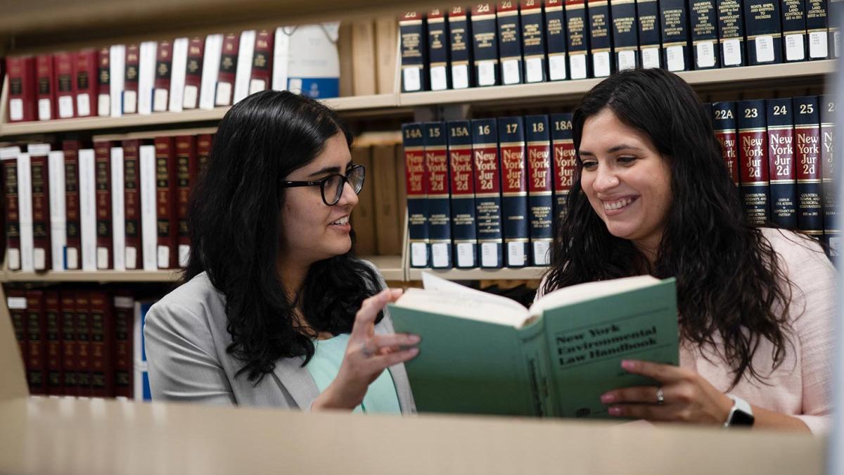 two students looking at a book at the Elisabeth Haub School of Law library