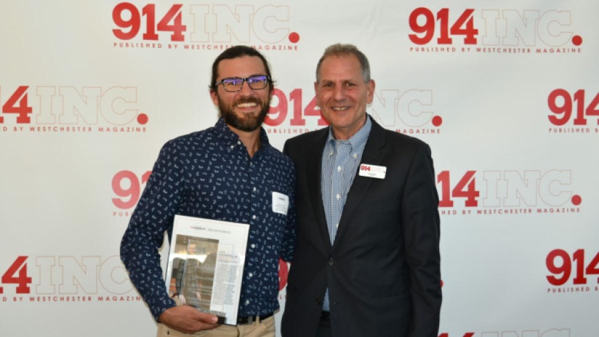 Jack Hornickel, a Staff Attorney with the Elisabeth Haub School of Law, holding an award and standing with another individual 