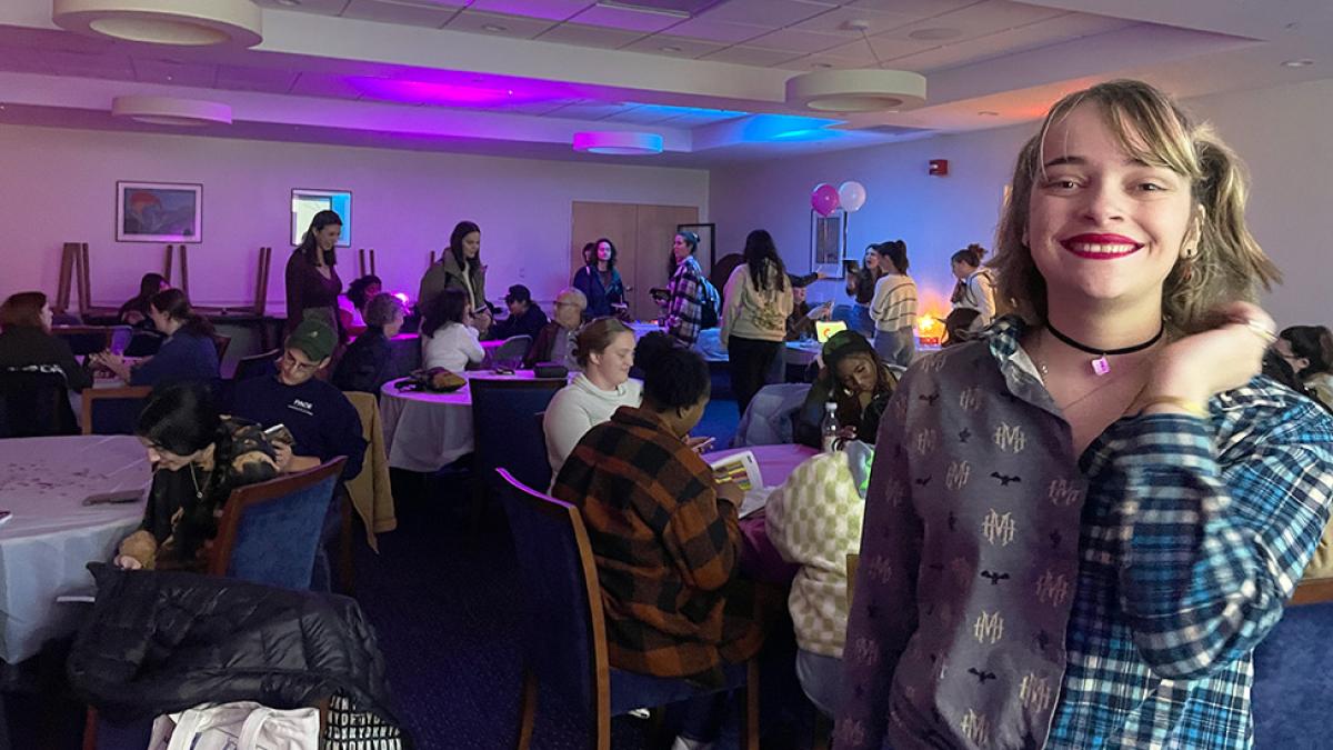 Female from Pace University's Writing and Cultural Studies department at a student event with people in the background