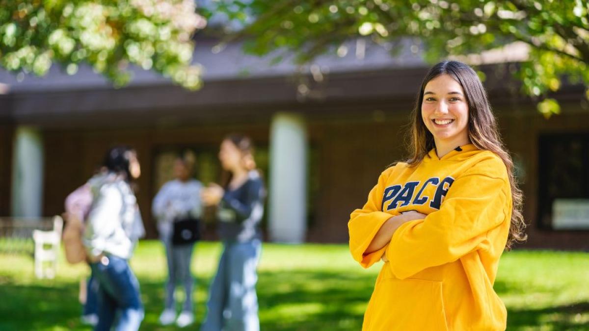 girl with pace sweater smiling on college campus 
