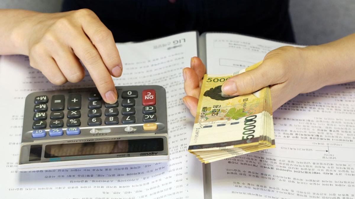 woman using calculator and holding a stack of paper currency