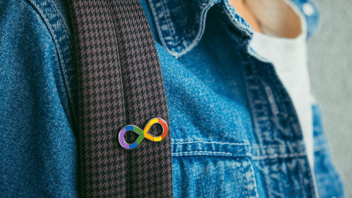 close-up of a neurodiversity awareness pin on a backpack strap. 