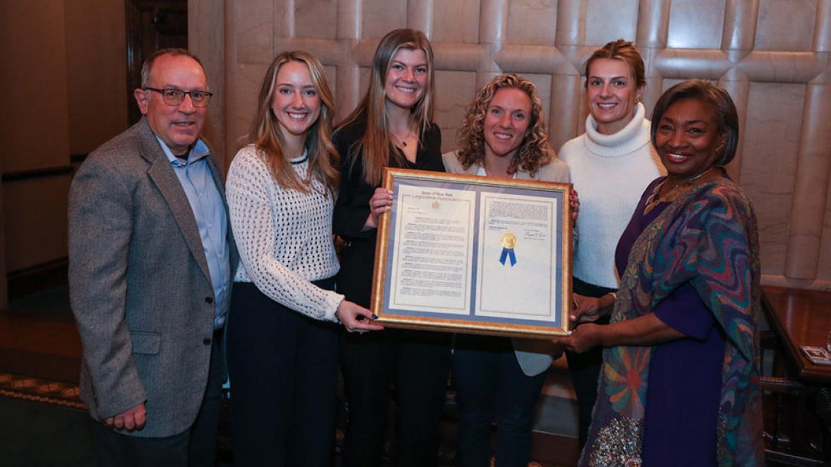 (From left) Volunteer Assistant Coach Robert Molfetta, Co-Captain Delilah Doyle, Co-Captain Kayla Conway, Head Coach Tricia Molfetta, Co-Captain Emma Rafferty, and Majority Leader Andrea Stewart-Cousins holding Senate Resolution No. 1667.