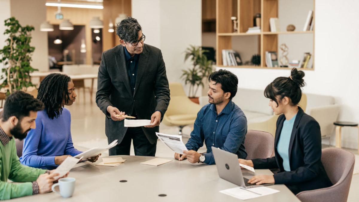 group of people working together at a table with papers and laptops