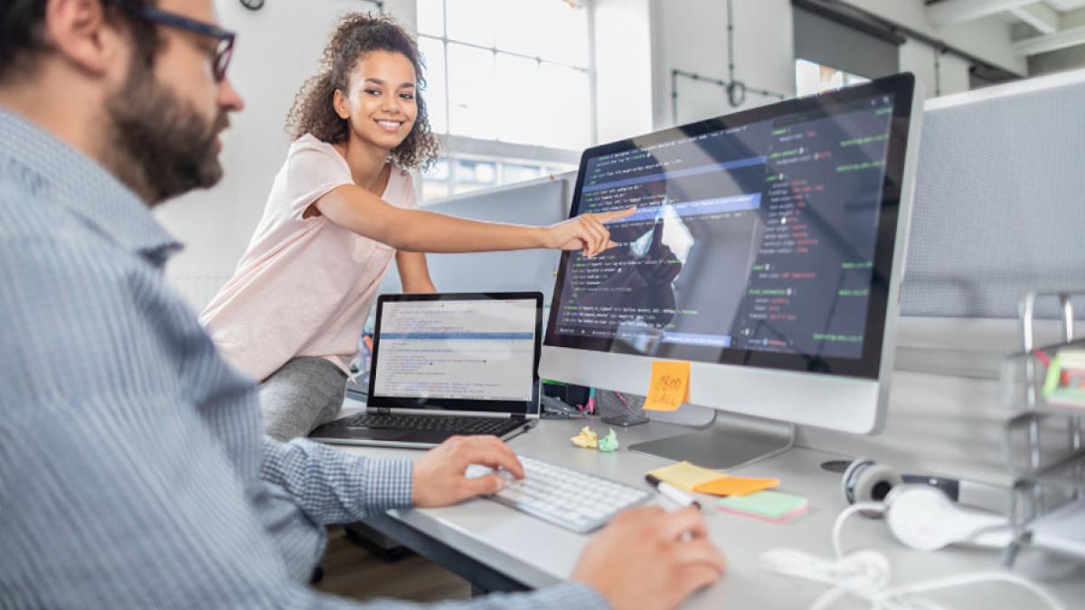 man and woman working together, looking at a computer screen