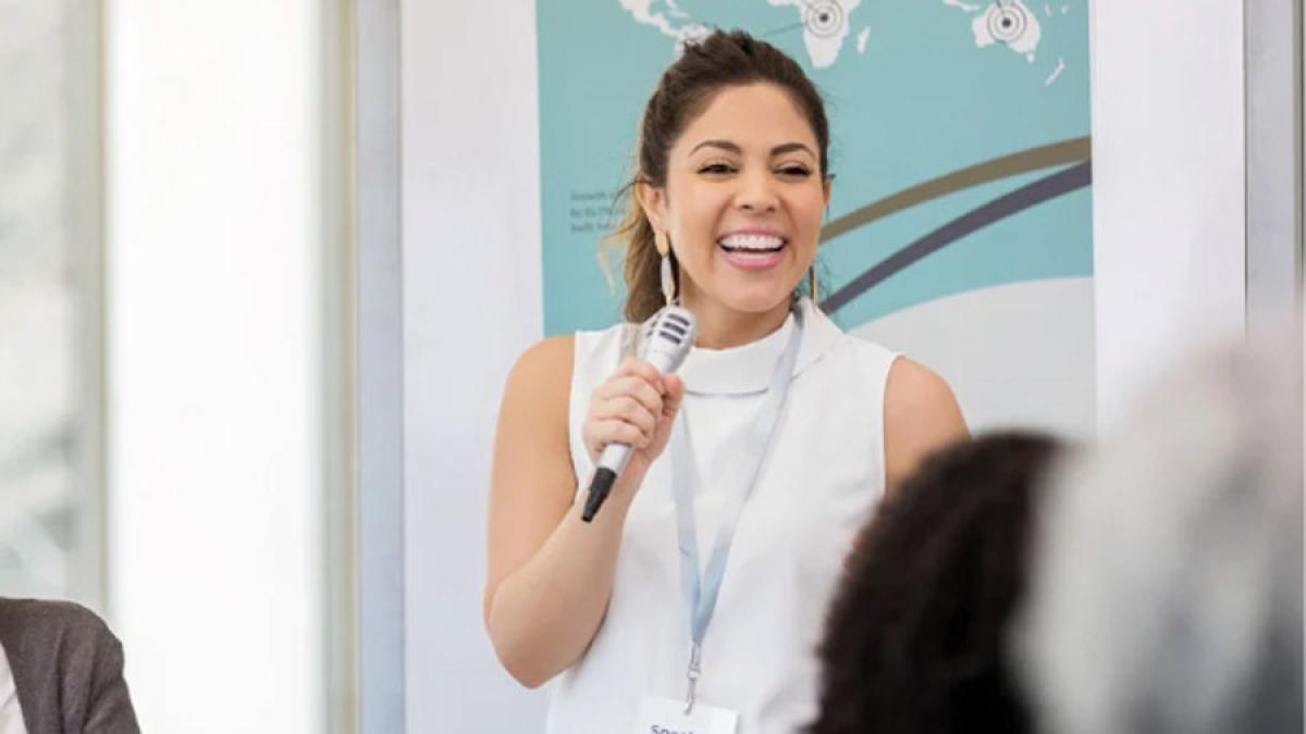 woman holding a microphone and speaking to an audience