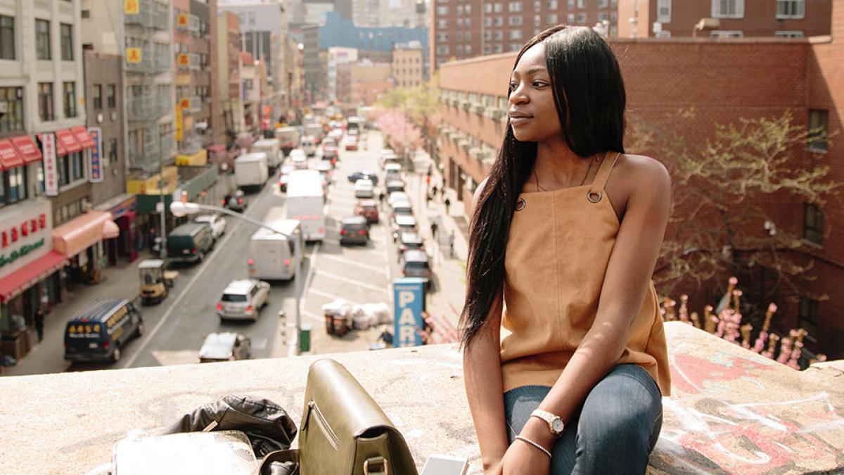 Pace University student sitting on a bridge in NYC.