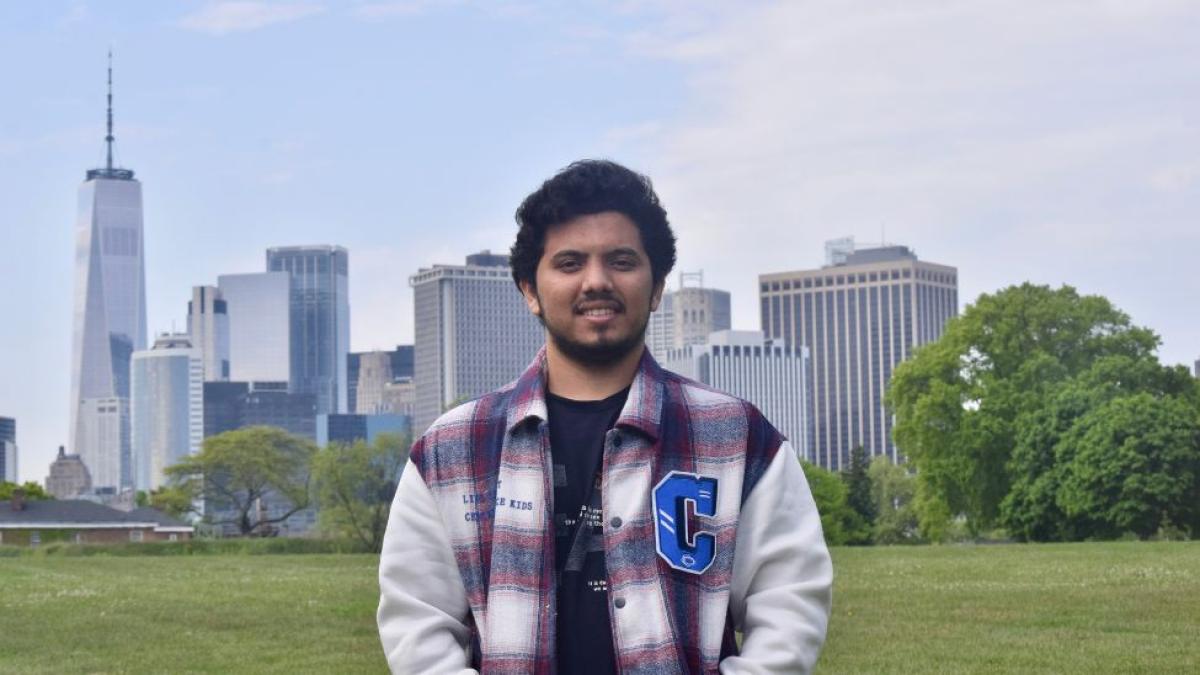 Pace student Darsh Joshi posing for a photo in a park, with the NYC skyline visible behind him.
