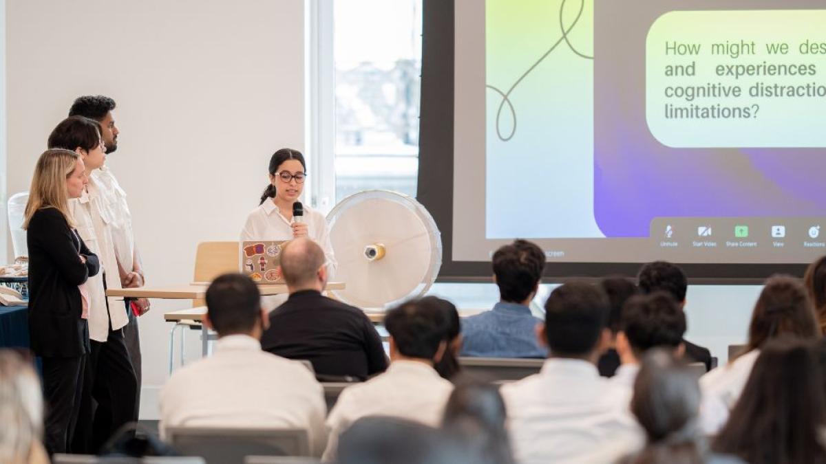 A group of Pace Seidenberg students showcasing a Powerpoint presentation of their Design Factory project to an audience at the Design Factory Gala.