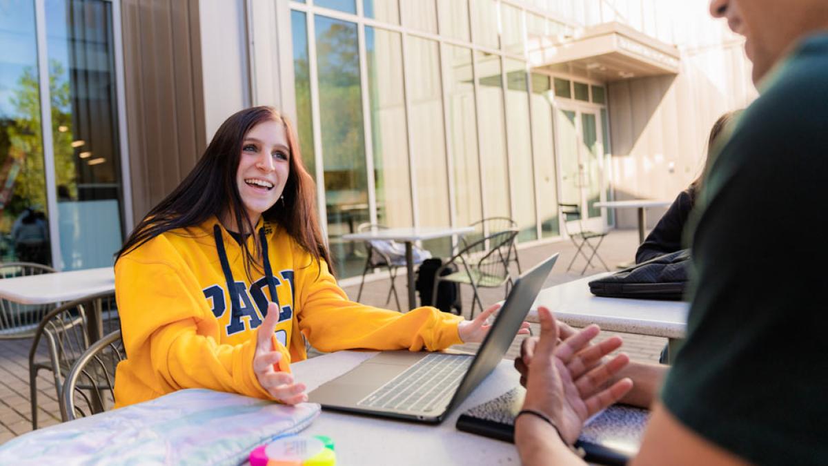 Pace University students talking and reviewing something on a computer. 