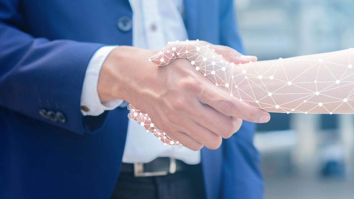 A man in a suit shaking hands with a cybernetic arm.