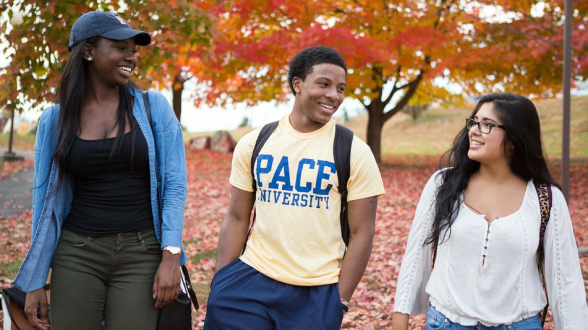 three Pace University students walking on the Pleasantville Campus near trees with fall foliage