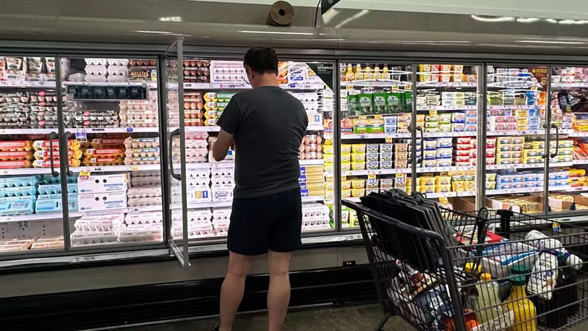 A man standing at the refrigerated shelves of a grocery store with a cart full of goods. AP Photo/Nam Y. Huh