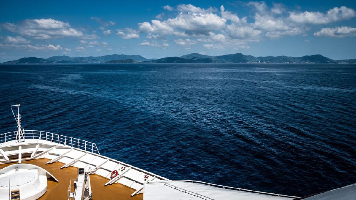 bow of cruise ship on open water with mountains in the distance