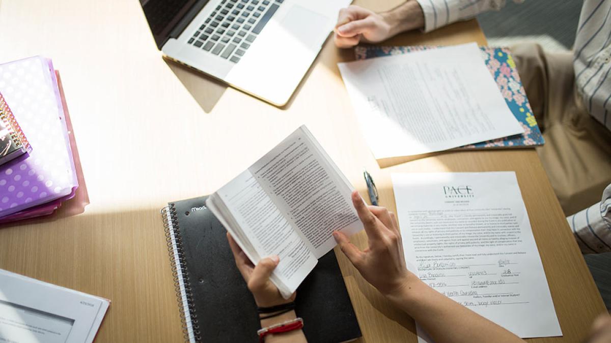 Two people at a desk looking at papers.