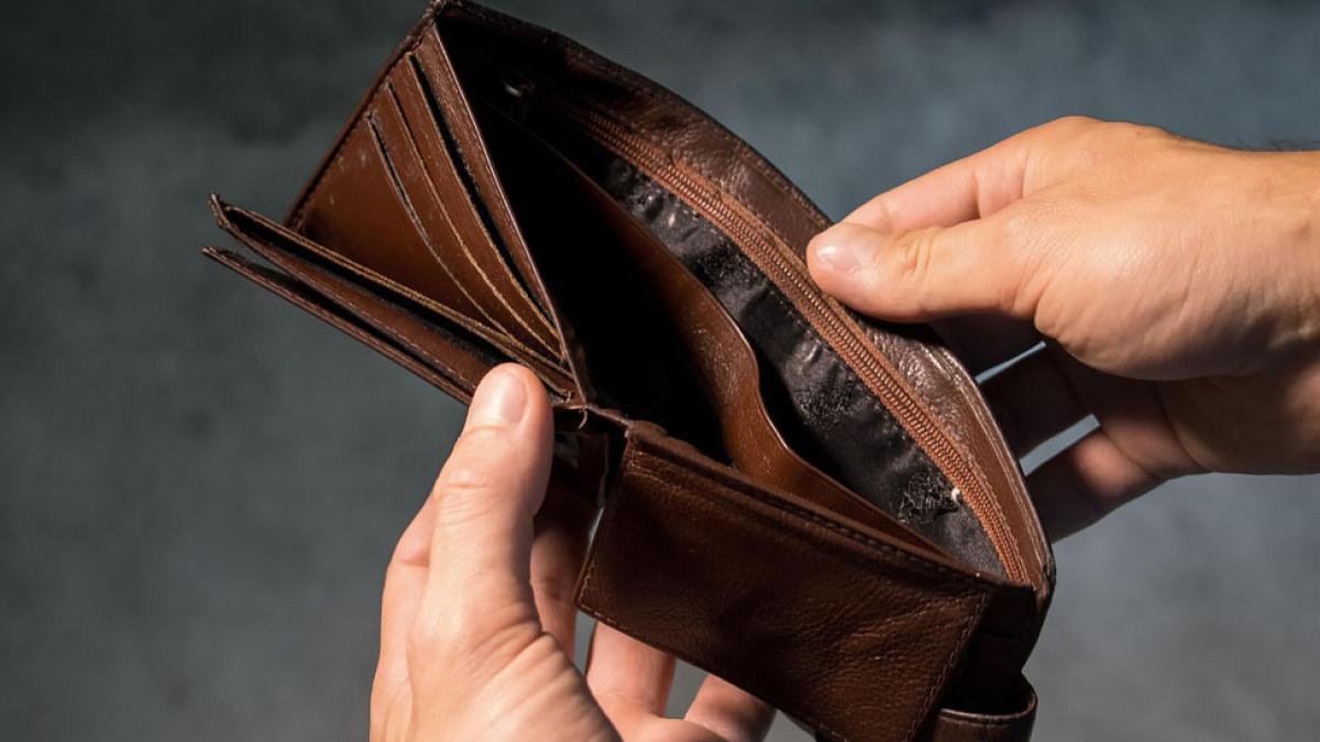 close up of man holding empty wallet representing the idea of "poverty"