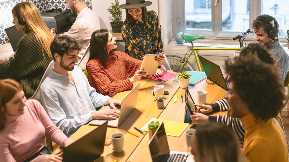 Group of Generation Z individuals working in a relaxed, collaborative setting with various communication devices