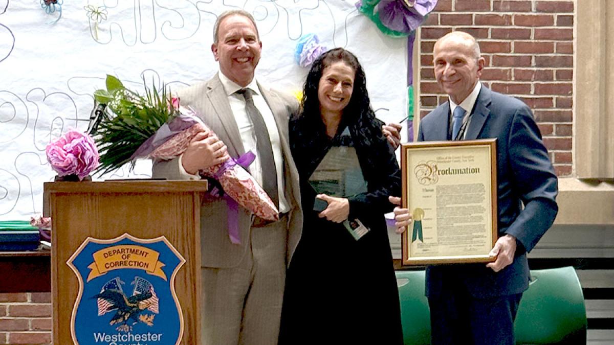 Pace University Professor of Criminal Justice and Security Kimberly Collica-Cox, PhD, standing with awards next to deputy Westchester County executives