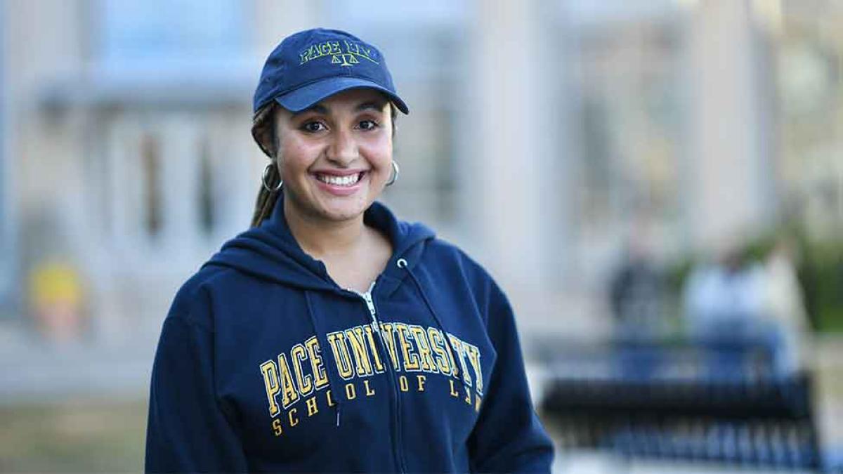 Female student in Haub Law sweatshirt and hat