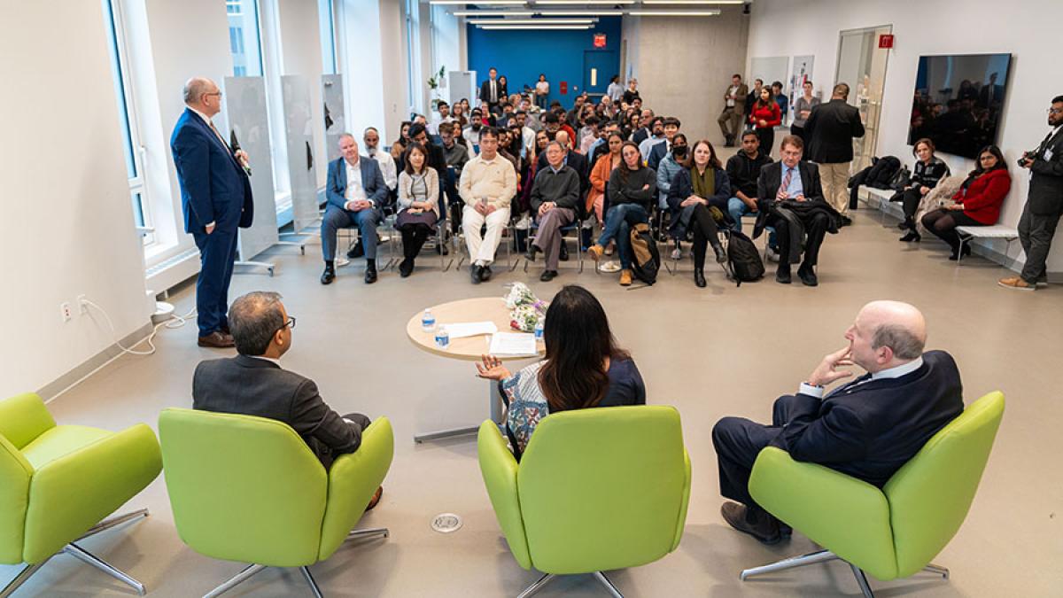 Group of people attending an event and listening to three speakers.