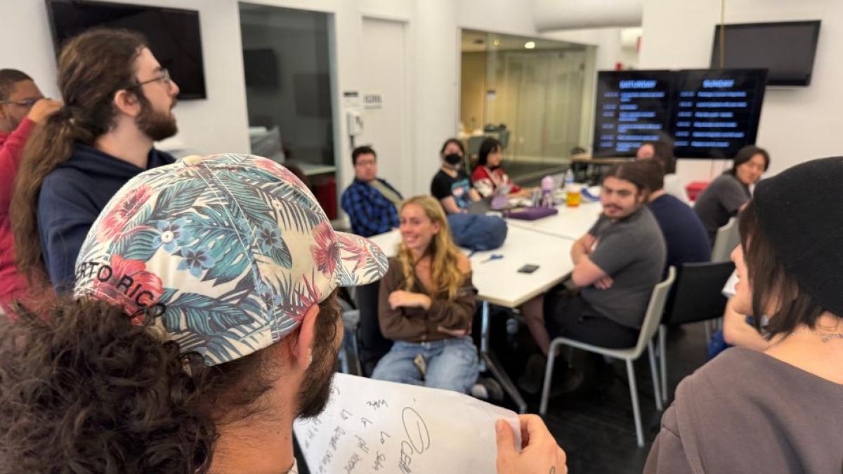 A group of Seidenberg students talking to a group of Parsons students while sitting around a table at the "Phenomenal" game jam.