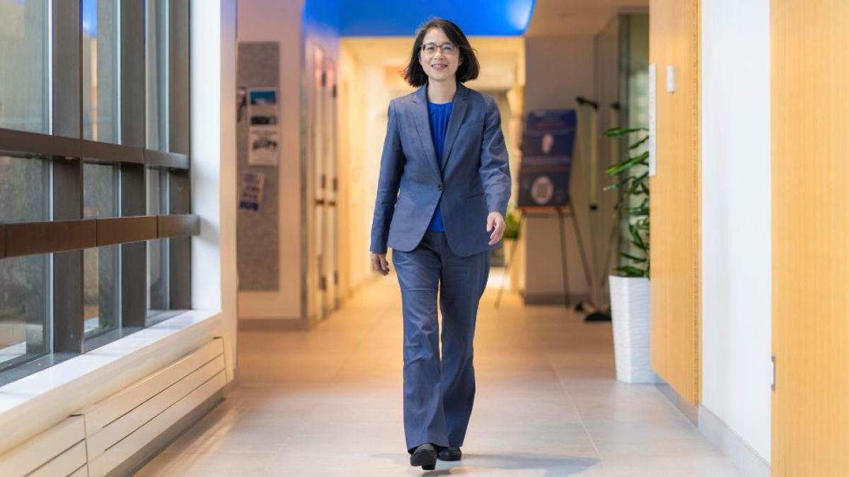 Interim Dean Li-Chiou Chen of Pace University's Seidenberg School of CSIS walking through a hallway while wearing a suit at Pace University's One Pace Plaza building.