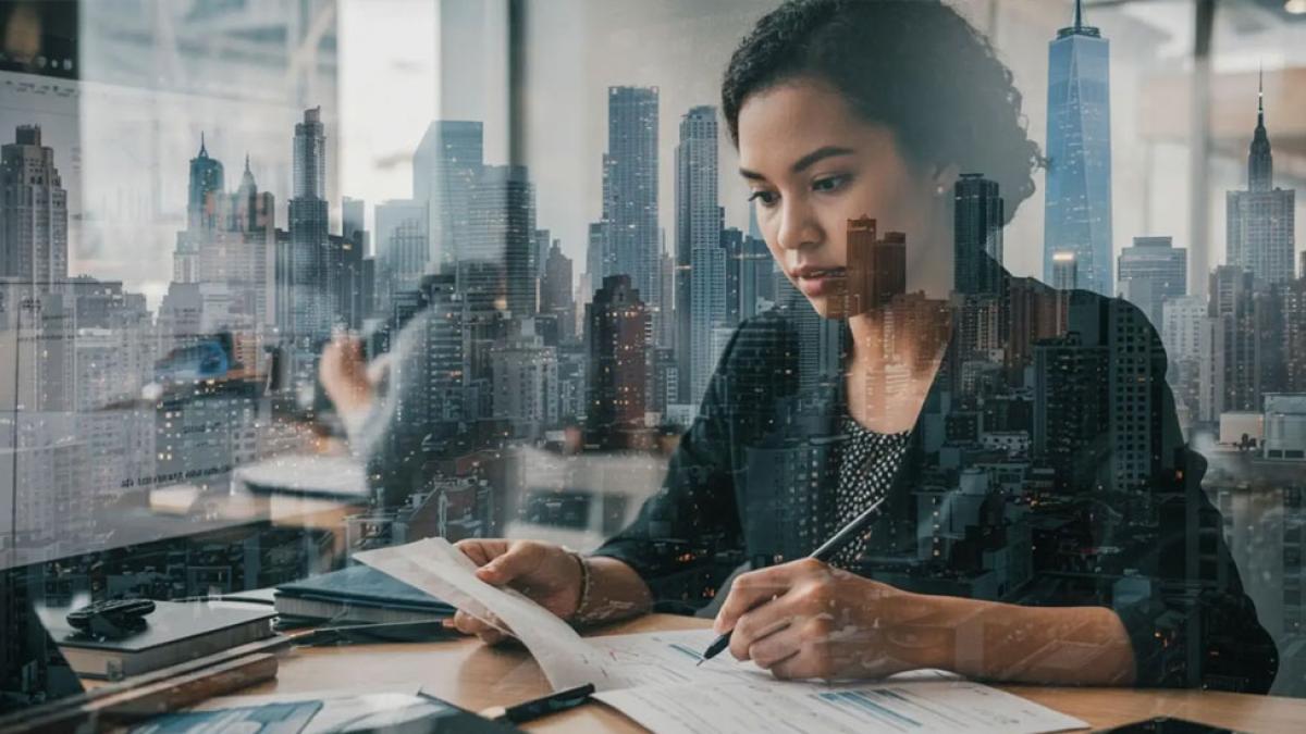 Double-exposure image of a woman working in a business setting with the NYC skyline in the background.