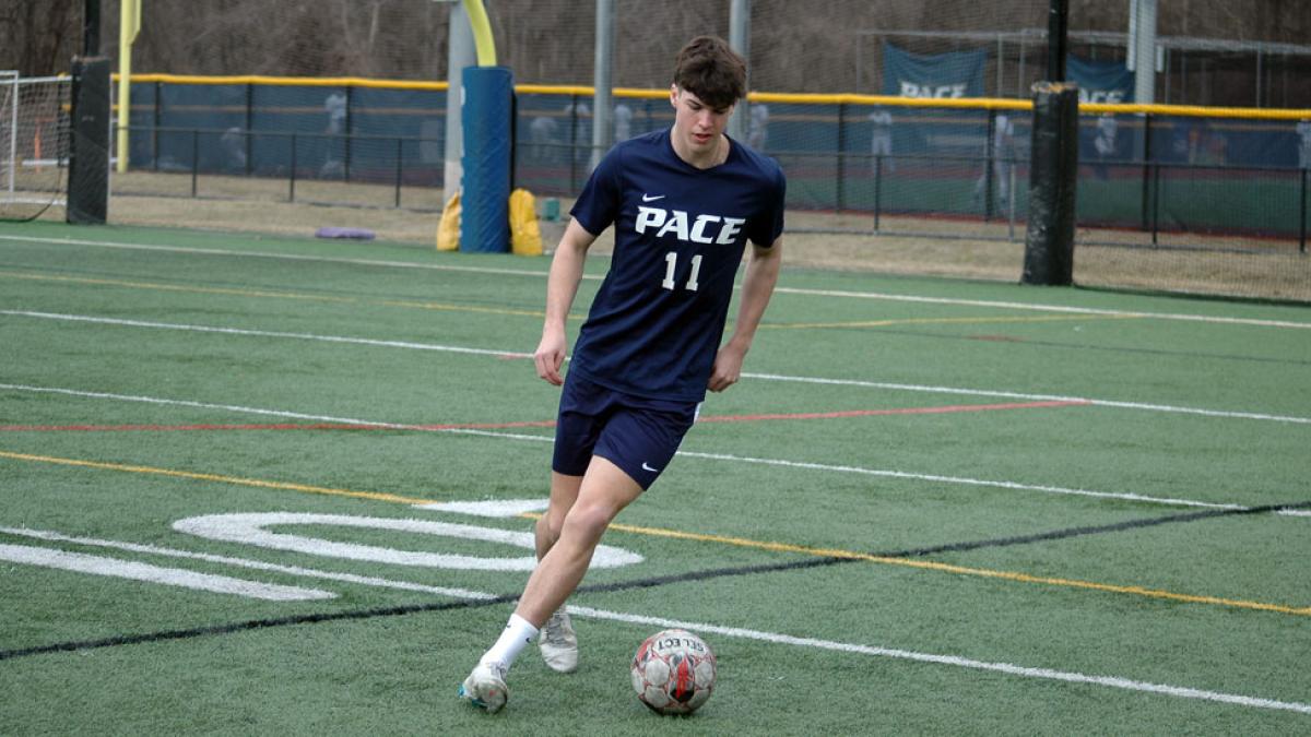 Pace student kicking a soccer ball.