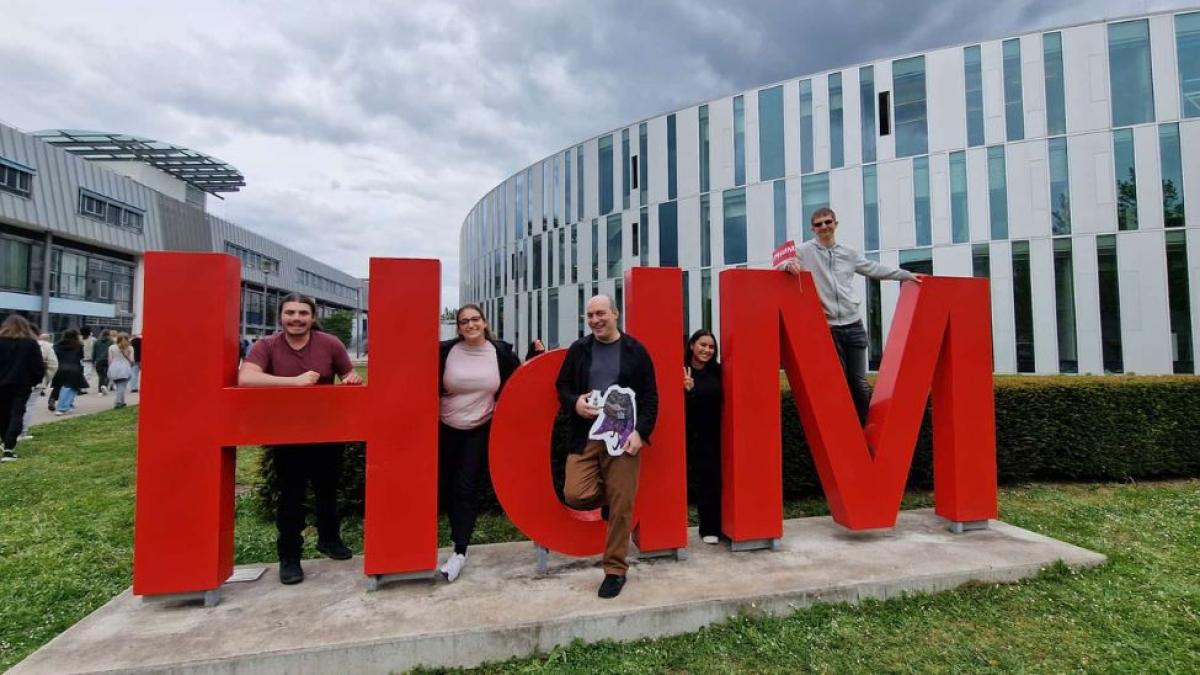 Pace Seidenberg professor Carmine Guida and a group of Seidenberg students posing for a photo in front of the FMX educational fair in Stuttgart, Germany.