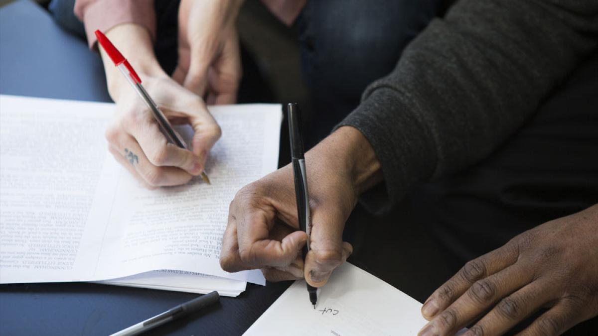 Two people writing on paper.