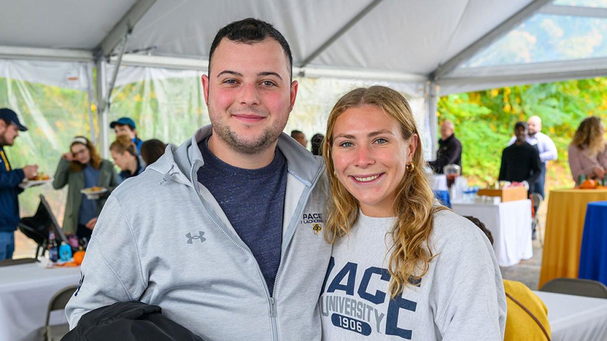 Two Pace University alumni smiling at the camera at Homecoming.