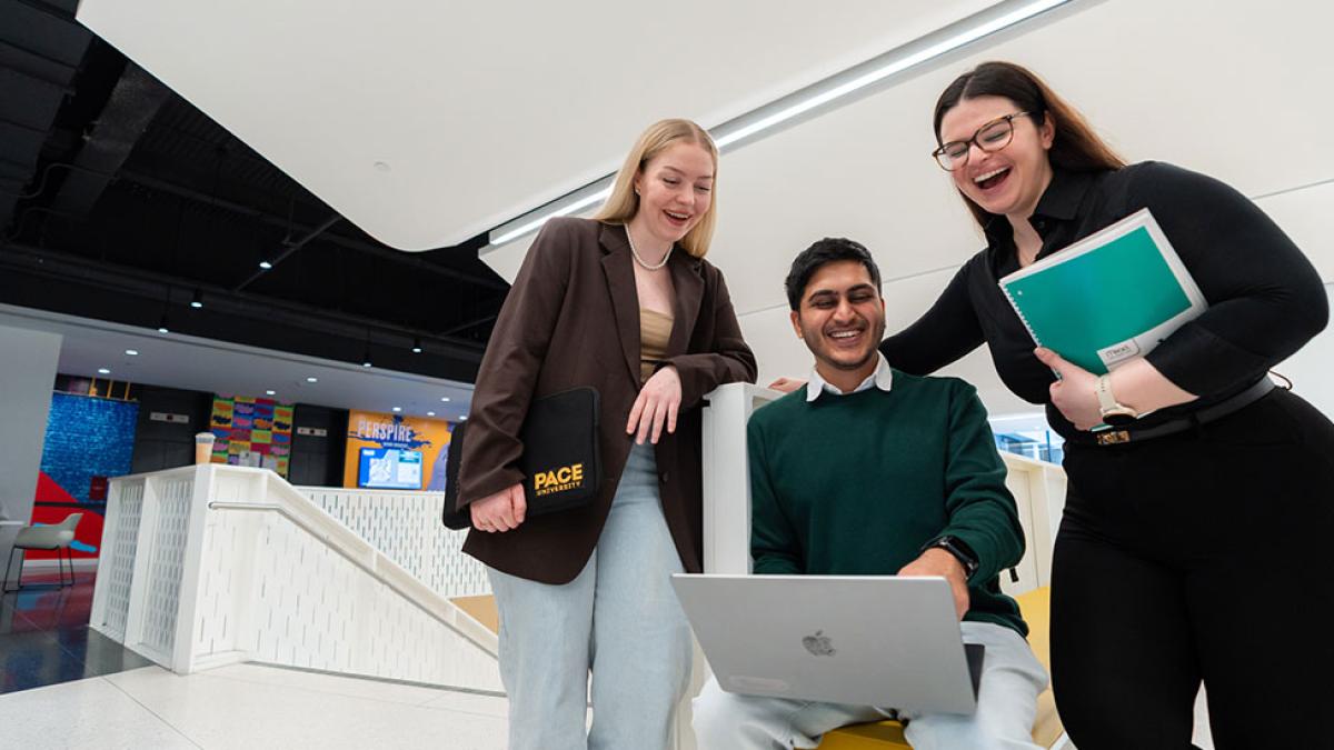 Pace students talking and looking at a laptop.