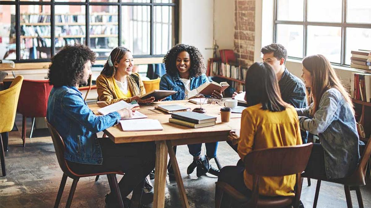 Group of diverse students sitting around a table talking