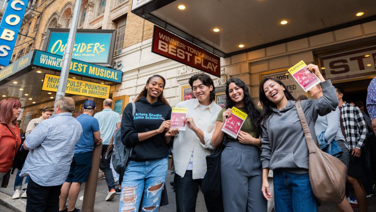 Pace students holding billboards in front of a Broadway theater.
