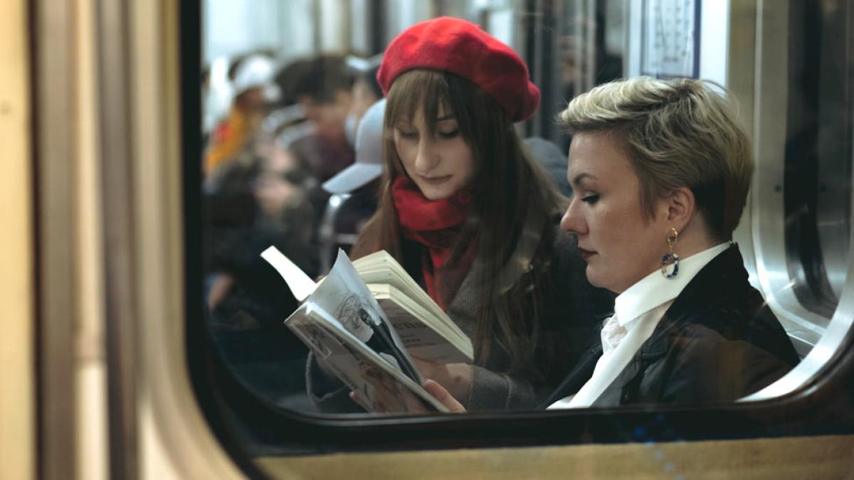 Women on the subway reading books.