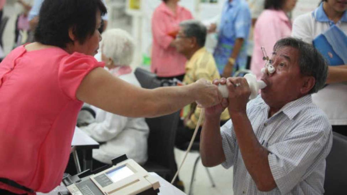 Doctor doing a lung health test of a middle aged man