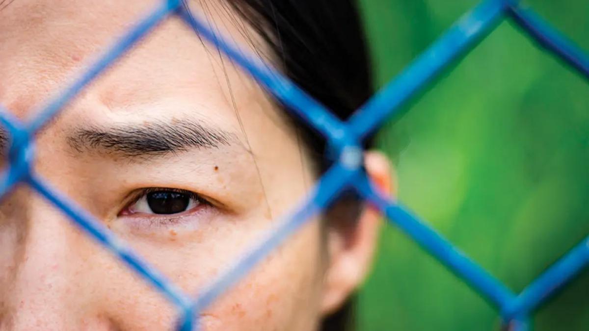 Person looking through a chain linked fence.