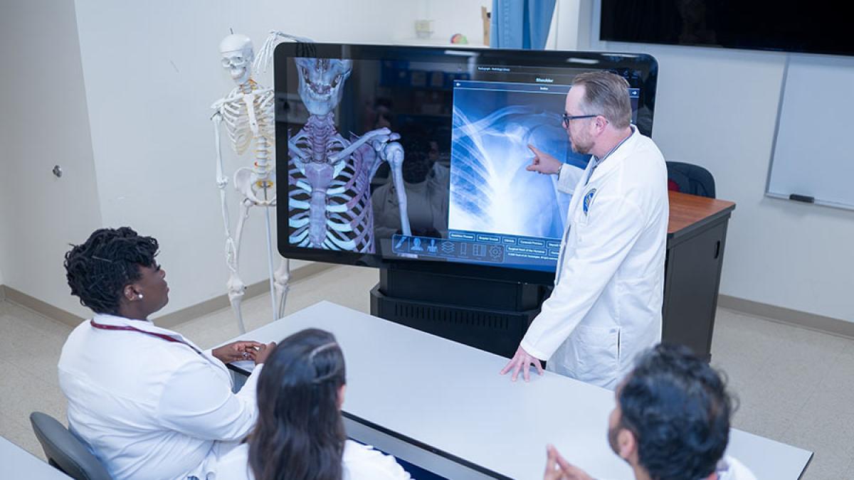 Students and professors using healthcare simulation equipment at the College of Health Professions at Pace University.