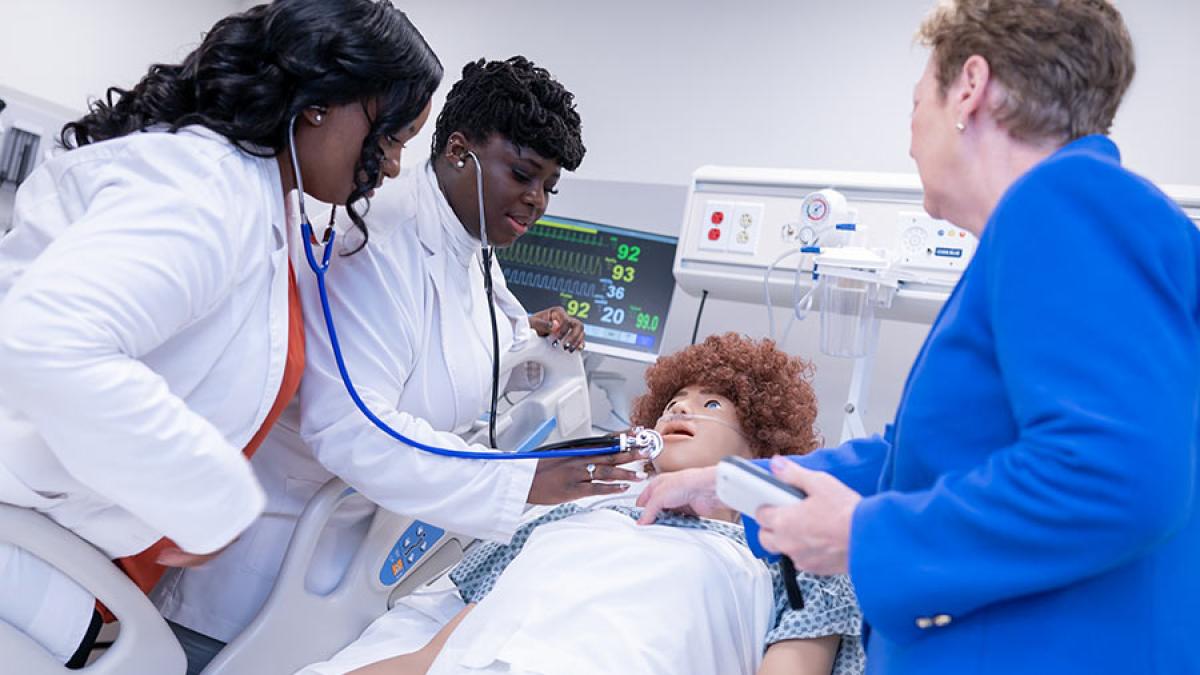 Two students and a professor using a patient simulator manikin at the College of Health Professions at Pace University