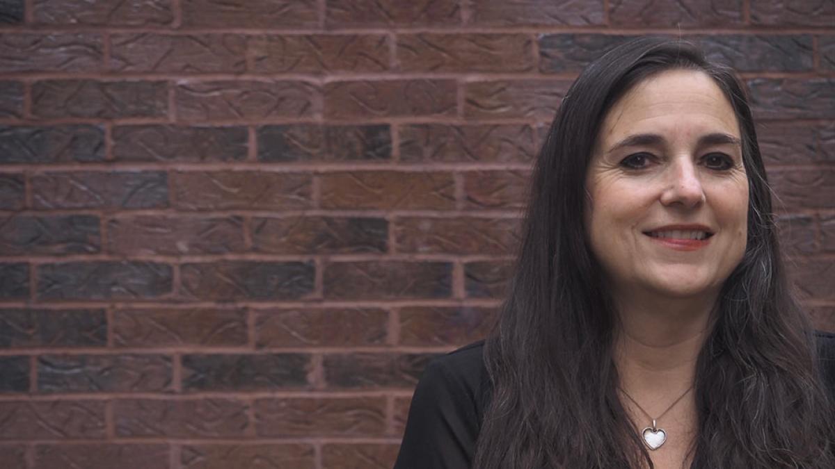 Pace University faculty Jessica Magaldi stands in front of a brick wall