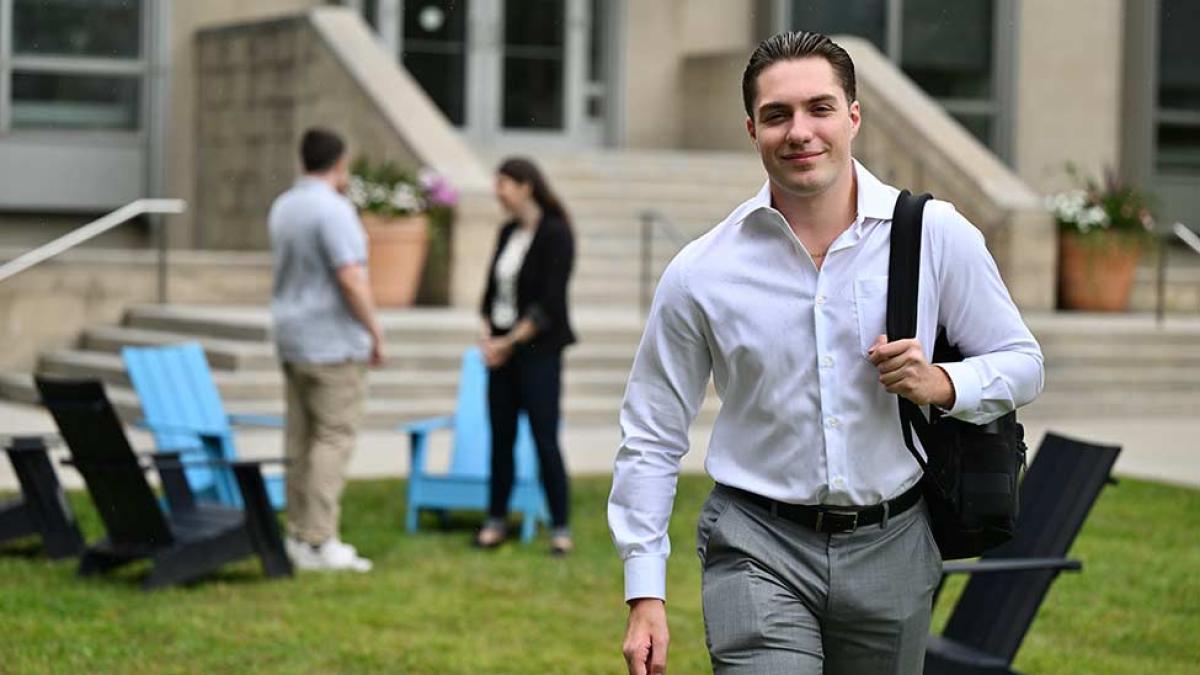 Male student dressed in business casual attire walking on campus