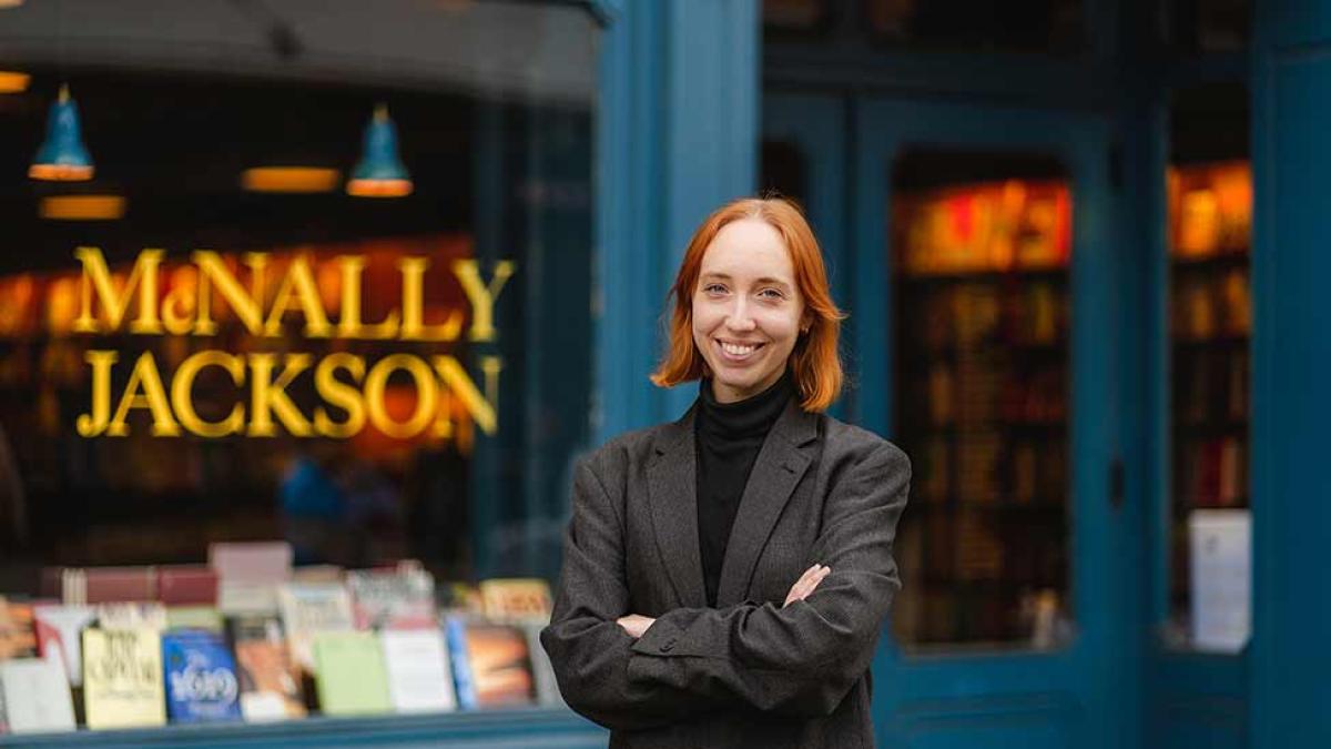Pace University student, smiling at the camera, standing in front of a bookstore.
