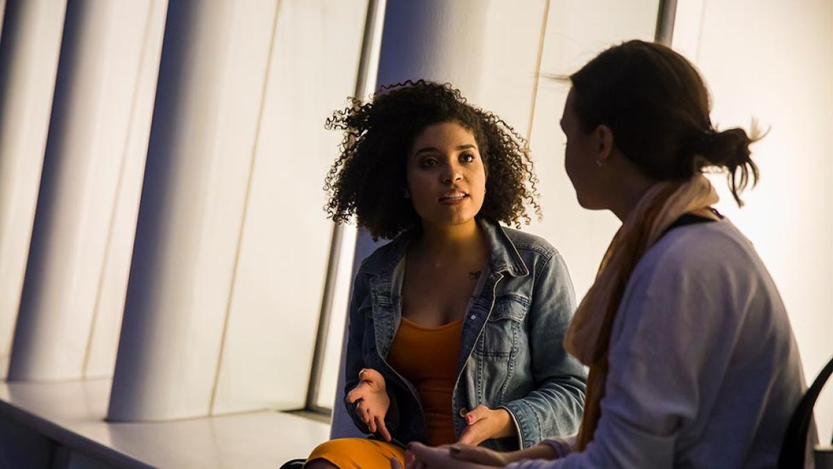 Two Pace University students sitting, talking with each other.