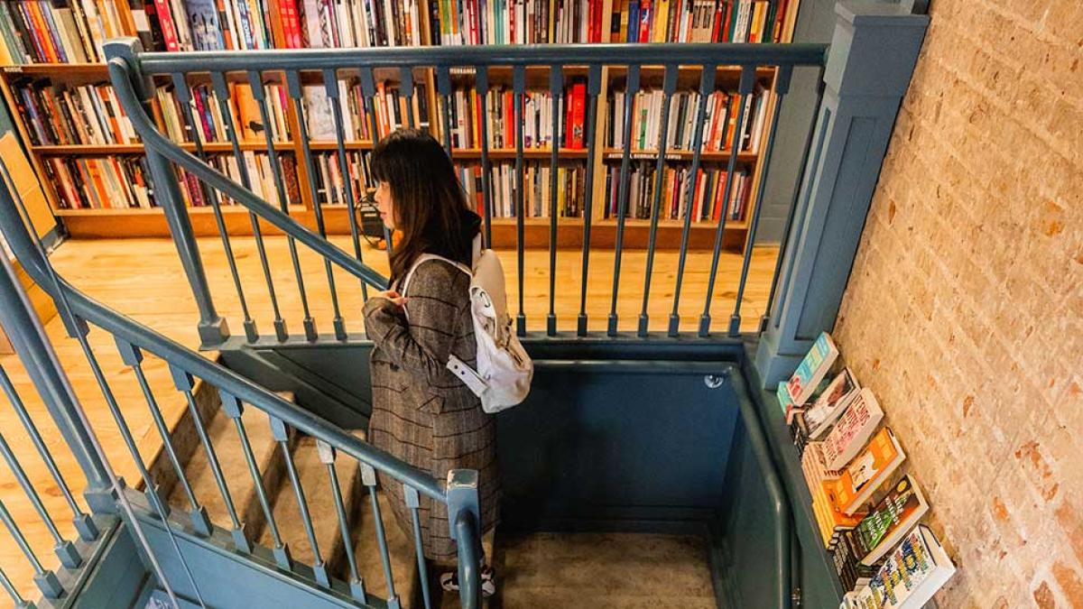 Pace University student going up the steps inside a bookstore.