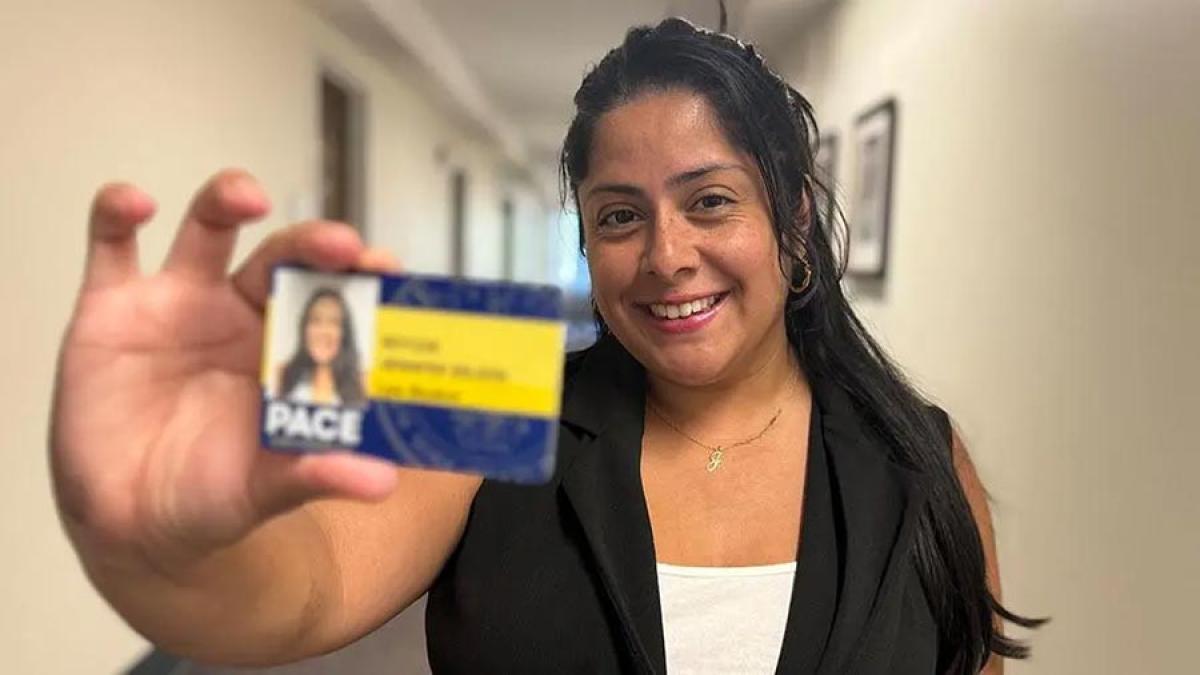 Pace University student smiling at the camera, showing her One Card.