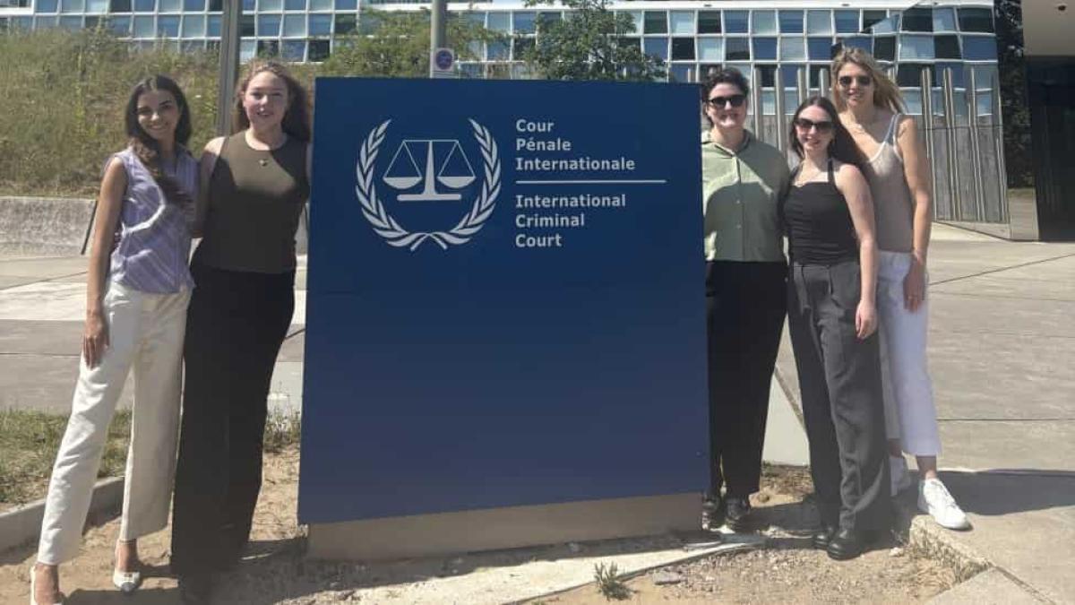 Elisabeth Haub School of Law at Pace University moot team standing in front of sign in the Hague
