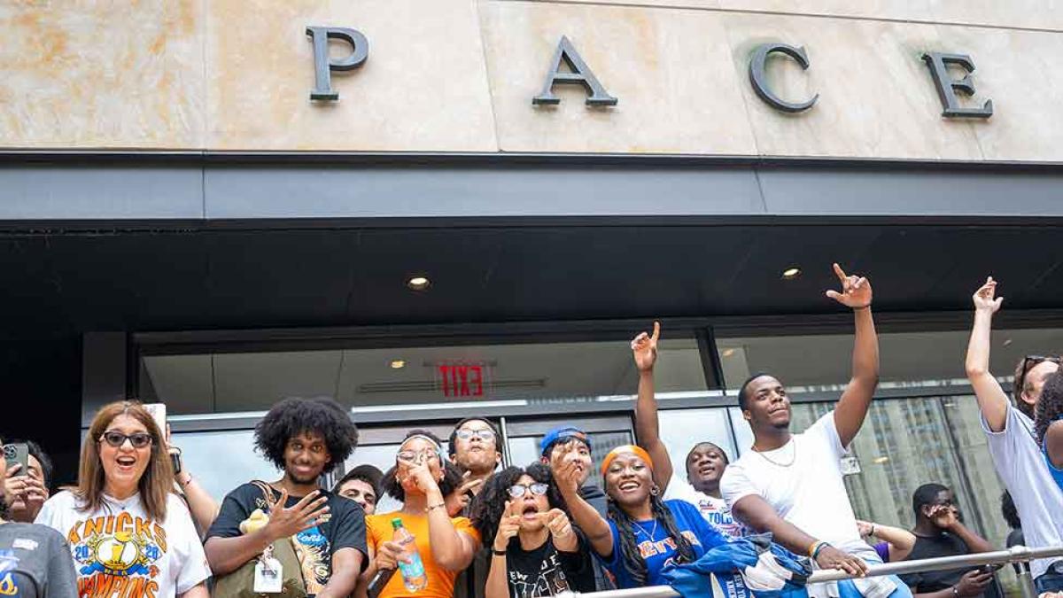 Knicks fans wave to the camera in front of One Pace Plaza