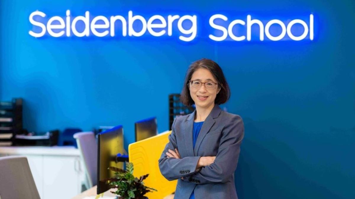 Seidenberg Dean Li-Chiou Chen in front of the school's neon sign