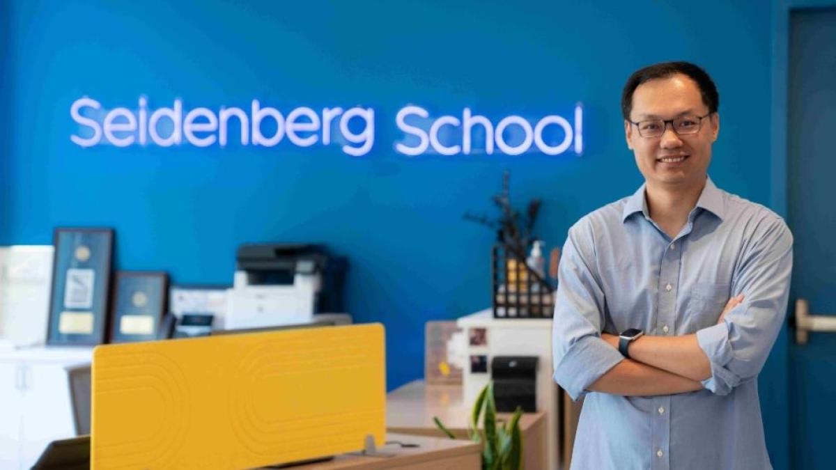 Seidenberg professor Zhan Zhang, PhD, in front of the school's neon sign
